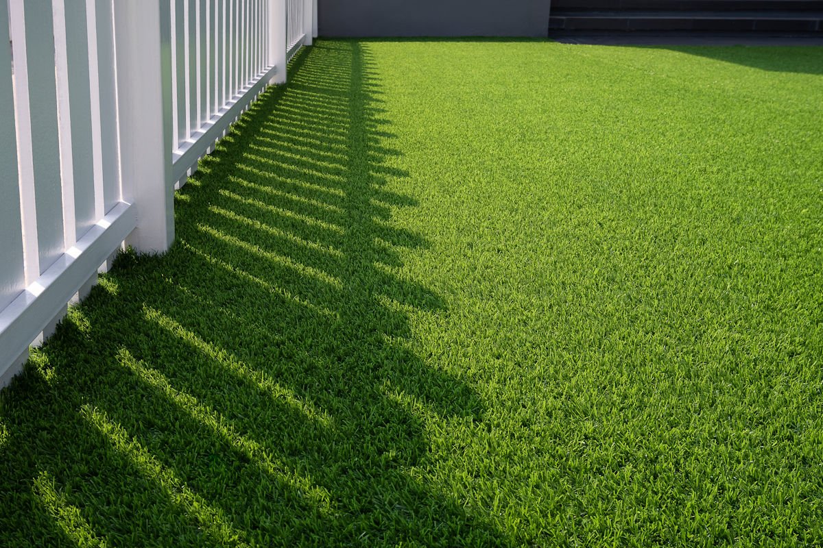 light coming through a fence onto an artificial turf lawn